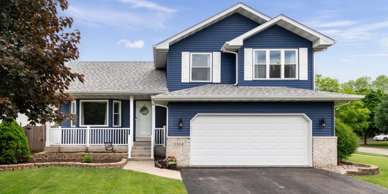 View of a house with newly installed blue siding and a white garage door, highlighting the enhanced curb appeal after remodeling.